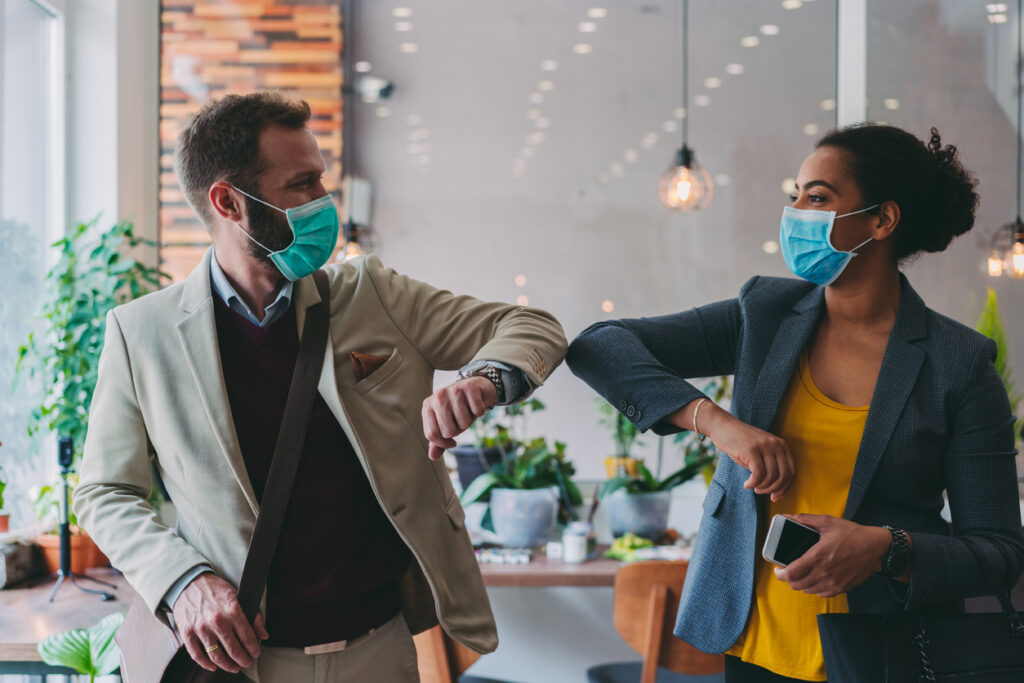 Two employees wearing COVID-19 masks at work, return to work during COVID-19